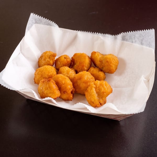 Golden-brown fried chicken nuggets in a white paper-lined basket on a dark surface.